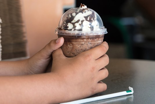 Child hands holding a coffee milk shake